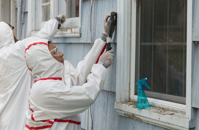 Two-house-painters-in-hazmat-suits-removing-lead-paint-from-an-old-house